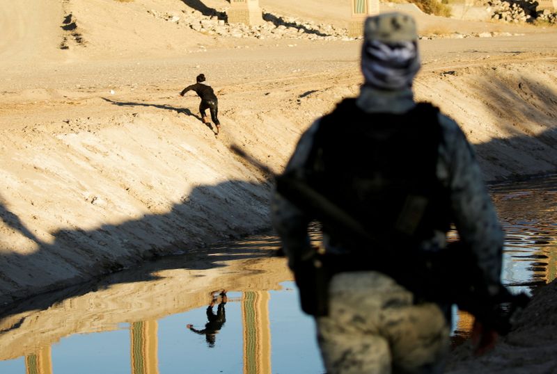 © Reuters. A member of the Mexican National Guard observes migrants after they crossed into El Paso, Texas, U.S., to turn themselves in to request asylum, as seen from Ciudad Juarez