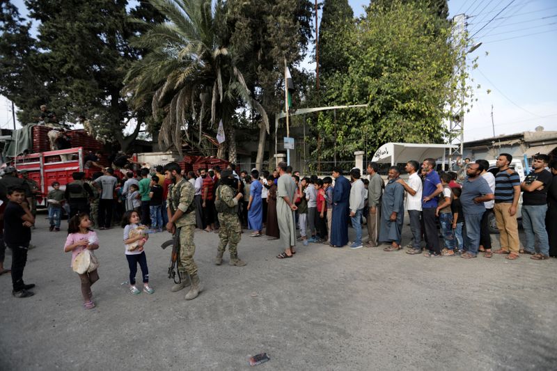 &copy; Reuters. FILE PHOTO: People stand in a queue to get bread in the border town of Tal Abyad