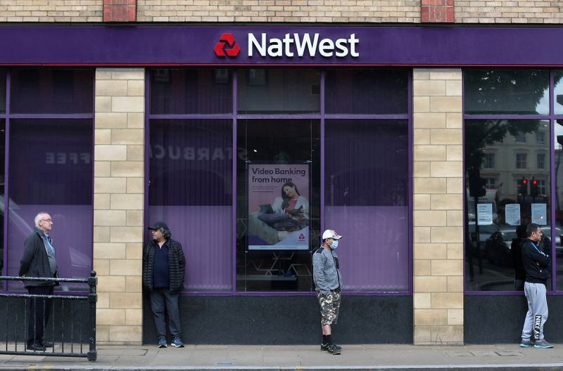 &copy; Reuters. FILE PHOTO: People maintain social distance while they queue outside a Natwest bank in Wimbledon