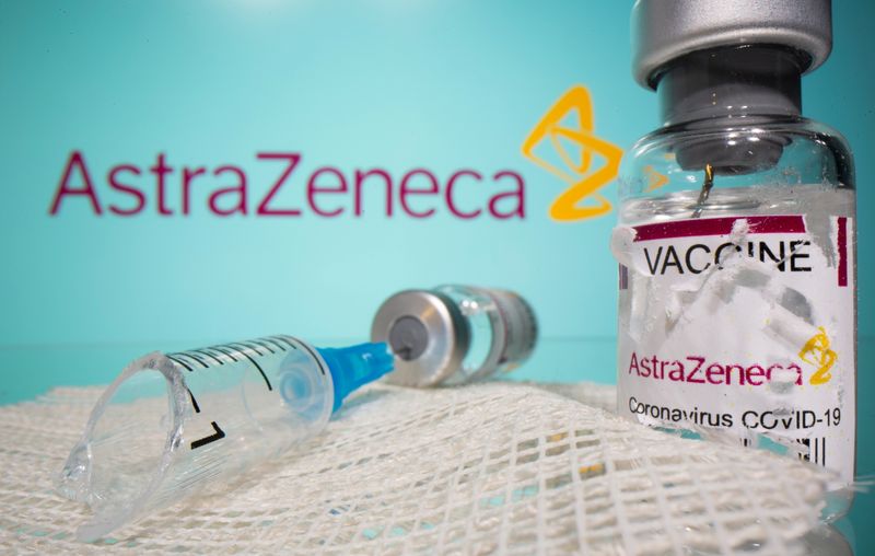 &copy; Reuters. Vial labelled with partially torn sticker &quot;AstraZeneca COVID-19 Coronavirus Vaccine&quot; and a broken syringe are seen in front of a displayed AstraZeneca logo in this illustration