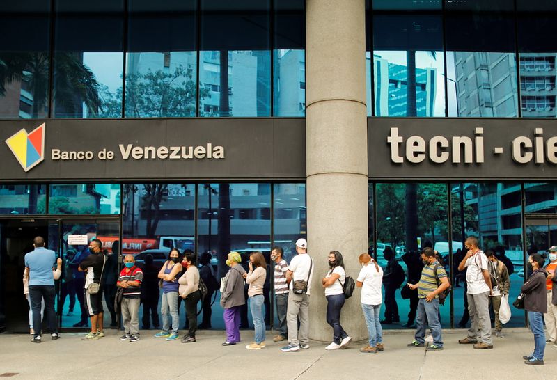 &copy; Reuters. Personas hacen fila fuera de una sucursal bancaria para retirar efectivo y obtener los nuevos billetes de mayor denominación, en Caracas, Venezuela