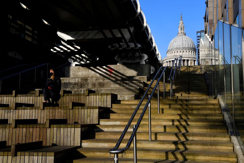 &copy; Reuters. FILE PHOTO: A woman wearing a protective face mask sits in the winter sunshine with St. Paul&apos;s Cathedral seen behind amidst a lockdown during the spread of the coronavirus disease (COVID-19) pandemic, London, Britain