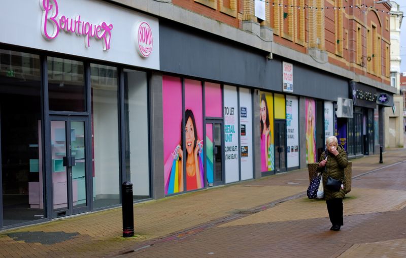 &copy; Reuters. A woman walks past a row of empty retail units on an empty shopping street in Blackpool