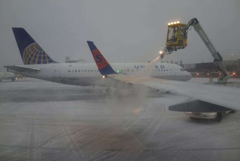 &copy; Reuters. FILE PHOTO: A Sun Country Airlines plane&apos;s wing is de-iced as a United Airlines plane waits at the de-icing station during a snowstorm at Logan International Airport in Boston