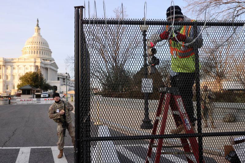 © Reuters. FILE PHOTO: Workers install razor wire atop the unscalable fence surrounding the U.S. Capitol in Washington