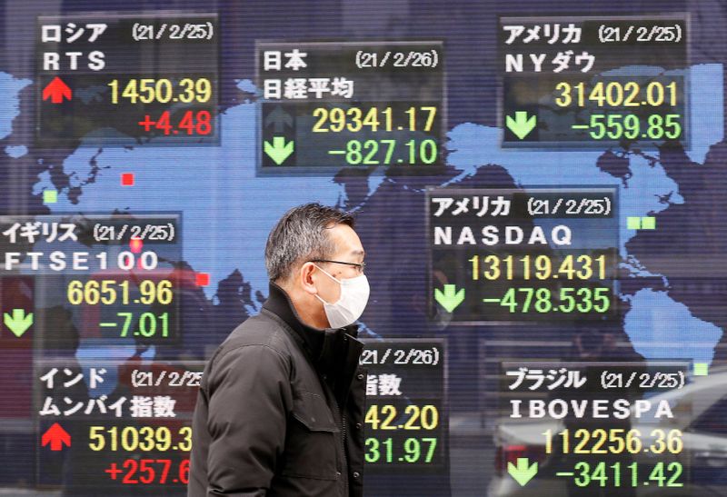 © Reuters. FILE PHOTO: A man walks past a stock quotation board at a brokerage in Tokyo, Japan