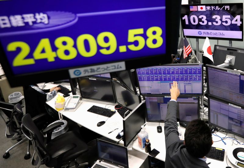 &copy; Reuters. An employee of the foreign exchange trading company works in front of monitors showing Japan&apos;s Nikkei share average and the Japanese yen exchange rate against the U.S. dollar at a dealing room in Tokyo