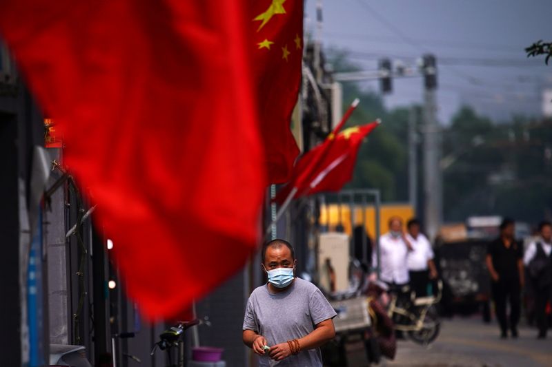 &copy; Reuters. Homem passa por prédio com bandeira da China em Pequim