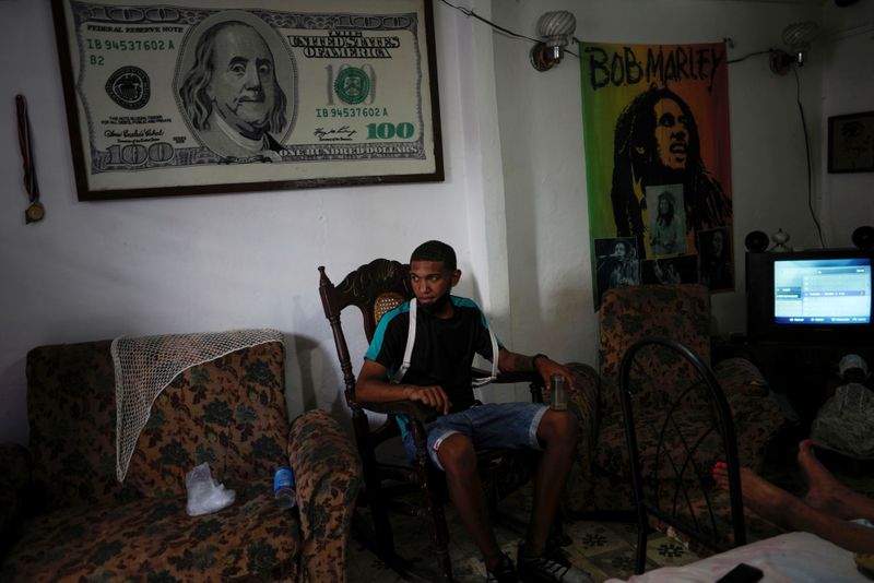 © Reuters. Student sits under image with the design of U.S. $100 bill in Havana