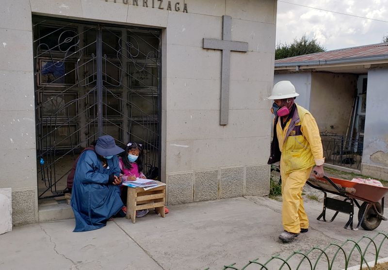 &copy; Reuters. Jeanete Alanoca, que trabalha em cemitério, ajuda a filha Neydy com atividade escolar em La Paz