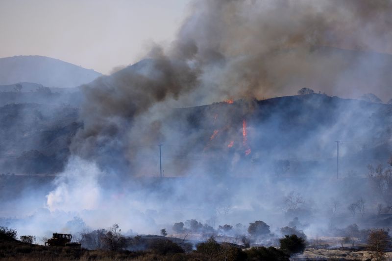 © Reuters. FILE PHOTO: A firefighting bulldozer battles the Bond Fire wildfire near Lake Irvine in Orange County, California