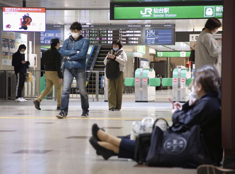 © Reuters. People sit on the floor at a station as train services are suspended following an earthquake in Sendai
