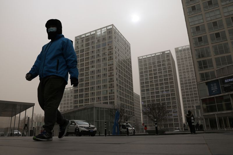 &copy; Reuters. Delivery worker wearing a face mask walks past an office and commercial complex in Beijing&apos;s Central Business District (CBD)