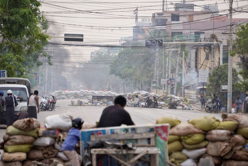 © Reuters. Protesters take cover behind barricades during a demonstration against the military coup in Mandalay