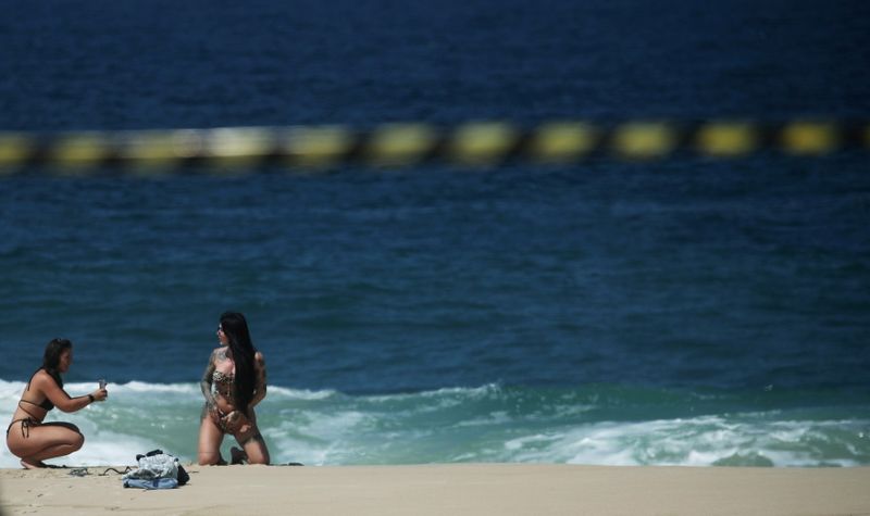 &copy; Reuters. Mulher posa para foto em praia do Rio de Janeiro, apesar de fechamento para conter Covid