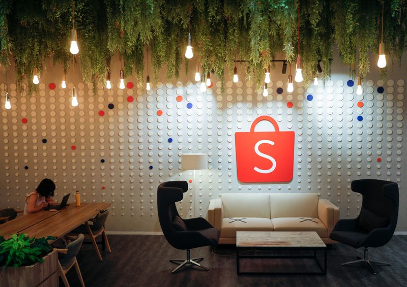 © Reuters. FILE PHOTO: A person sits near a sign of Shopee at its office in Singapore