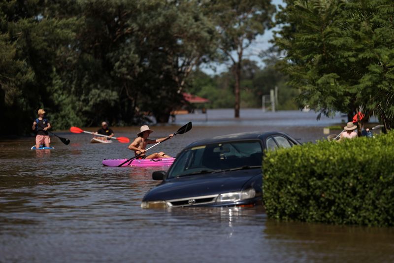 &copy; Reuters. Personas con kayaks y tablas de paddle navegan por un barrio residencial inundado en Sídney, Australia, 24 de marzo de 2021.  REUTERS/Loren Elliott