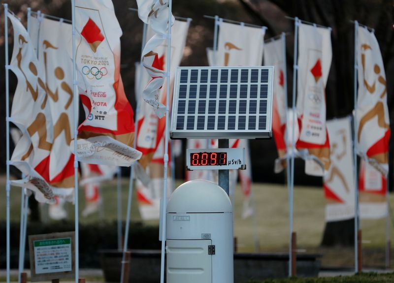 © Reuters. A Geiger counter is seen next to Tokyo 2020 Olympic Games flags at a park in Iwaki