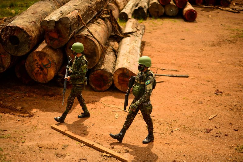 &copy; Reuters. Soldados do Exército caminham perto de pilha de madeira extraída ilegalmente da Amazônia em Porto Velho, Rondônia