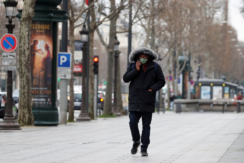 &copy; Reuters. FILE PHOTO: A man wearing a protective face mask walks on the Champs Elysees in Paris