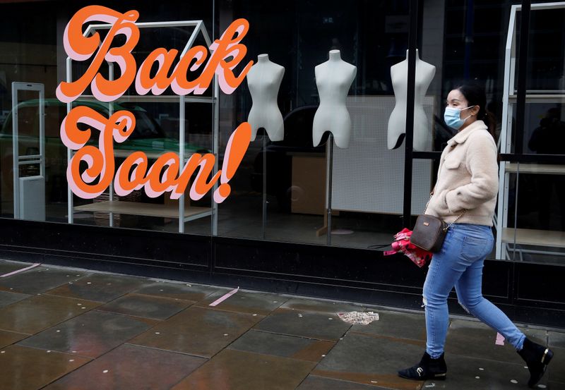 © Reuters. FILE PHOTO: A woman wears a face mask as she walks past a closed retail unit amid the outbreak of the coronavirus disease (COVID-19) in Manchester