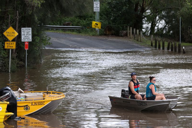 © Reuters. People in a boat navigate floodwaters resulting from prolonged rains northwest of Sydney in Wisemans Ferry