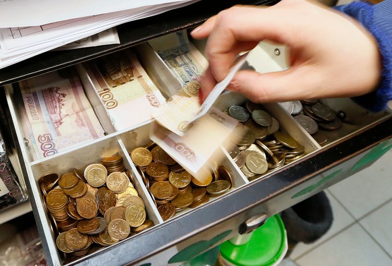 &copy; Reuters. A vendor places a Russian 100-rouble banknote into a cash register at a houseware shop in Krasnoyarsk