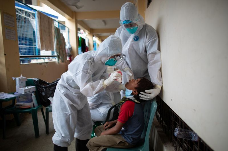 &copy; Reuters. FOTO DE ARCHIVO: Dos trabajadores sanitarios en EPI realizan un test de COVID-19 en una escuela de Rodríguez
