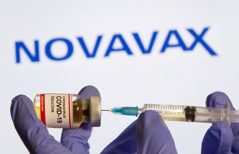 &copy; Reuters. FILE PHOTO: A woman holds a small bottle labeled with a &quot;Coronavirus COVID-19 Vaccine&quot; sticker and a medical syringe in front of displayed Novavax logo in this illustration