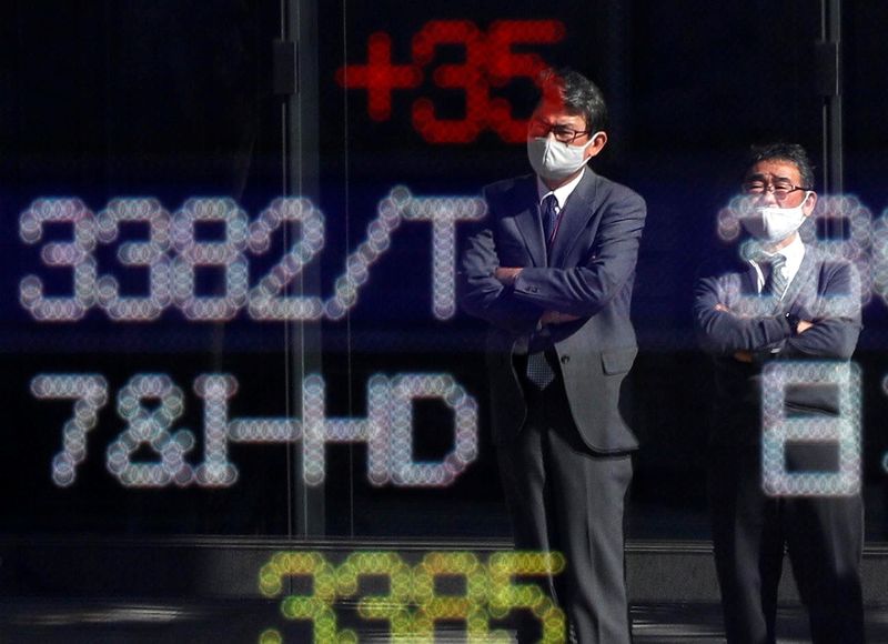 &copy; Reuters. Un uomo riflesso su uno schermo nel distretto finanziario di Tokyo