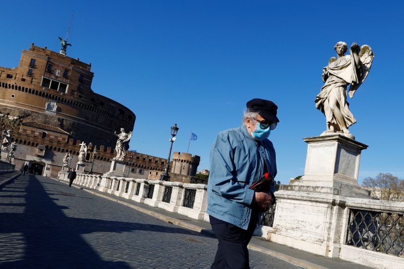 &copy; Reuters. Un uomo con indosso la mascherina attraversa Ponte Sant&apos;Angelo a Roma