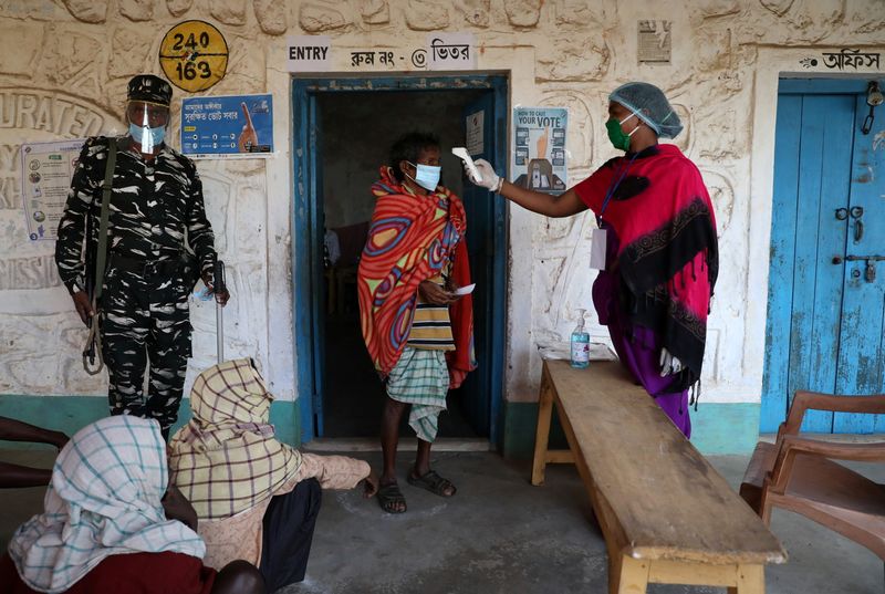 &copy; Reuters. A woman checks the temperature of a voter before he casts his vote at a polling booth in Purulia