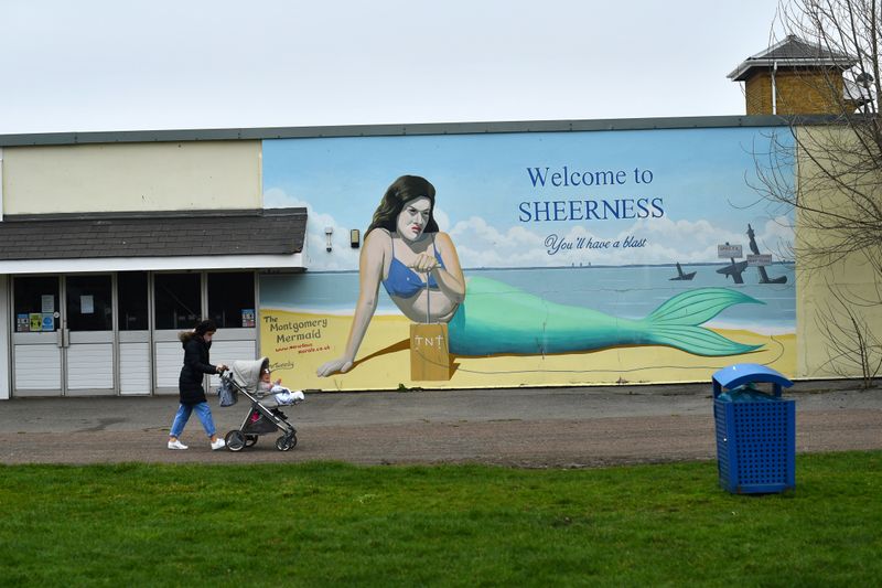 &copy; Reuters. Person walks with a pushchair past a mural of The Montgomery Mermaid in Sheerness, on the Isle of Sheppey