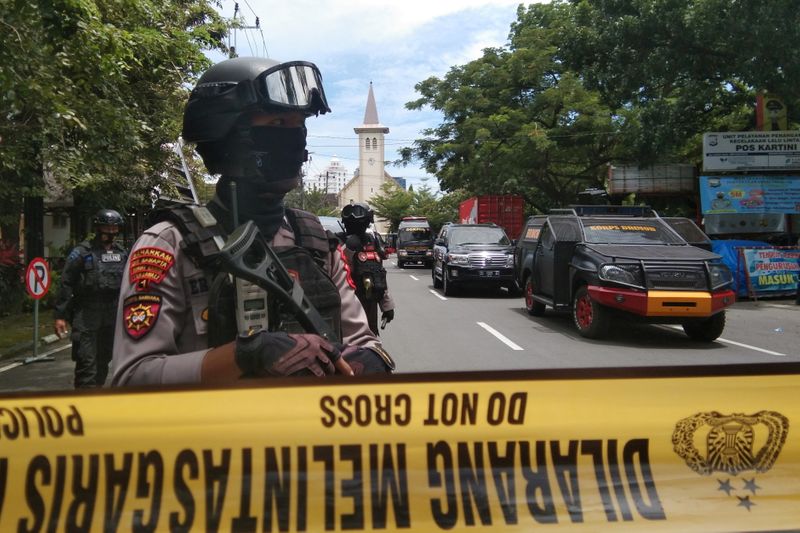 &copy; Reuters. Armed police officers stand guard along a closed road following an explosion outside a Catholic church in Makassar