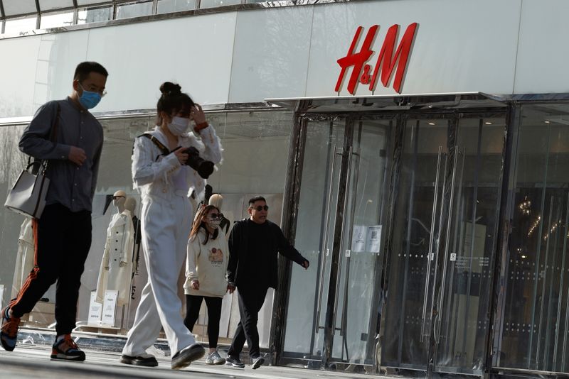 &copy; Reuters. Personas pasan por delante de una tienda de H&amp;M en una zona comercial de Pekín, China