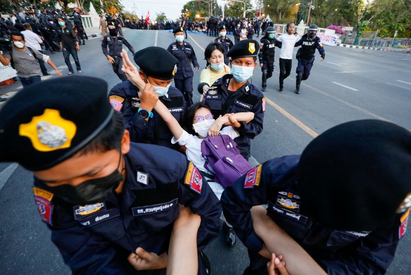 &copy; Reuters. A pro-democracy protester flashes the three-finger salute while she is detained by police officers in front of the Government House during a rally in Bangkok