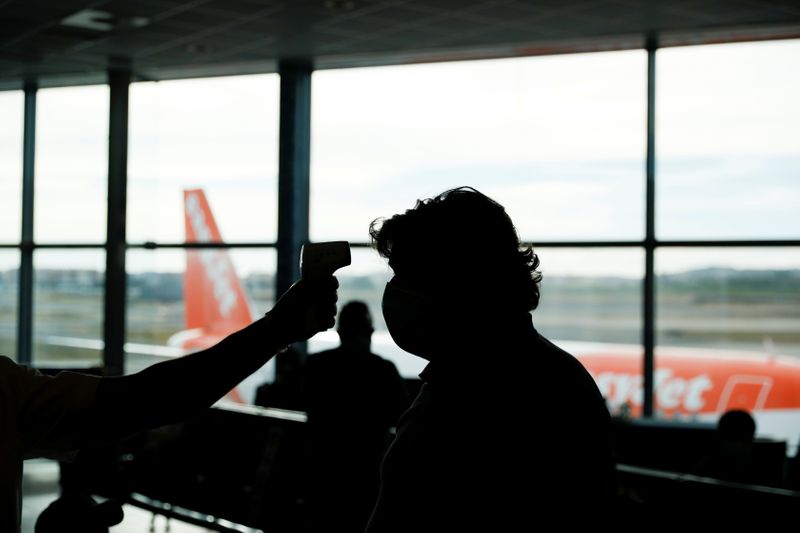 &copy; Reuters. Funcionário checa temperatura de passageiro antes da entrada em avião no aeroporto de Lisboa