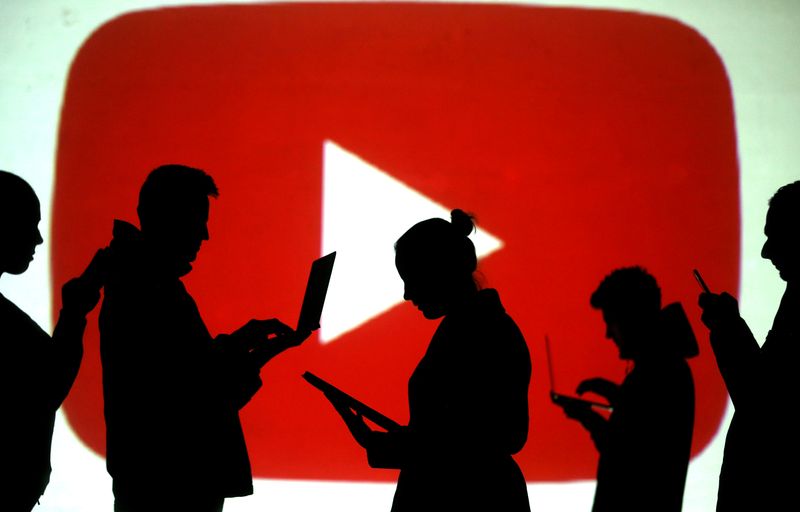 &copy; Reuters. FILE PHOTO: Silhouettes of laptop and mobile device users next to a screen projection of the YouTube logo in this picture illustration