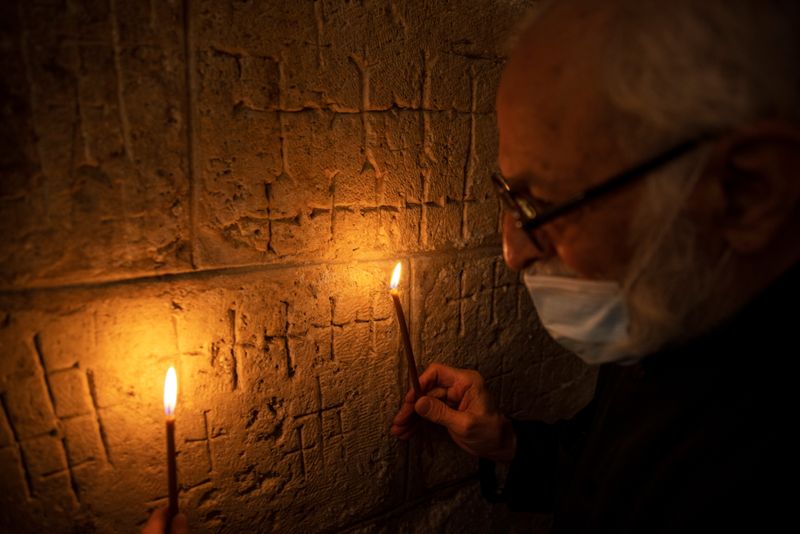 &copy; Reuters. Father Samuel Aghoyan, the Armenian superior at the Church of the Holy Sepulchre holds candles to illuminate crosses etched into the ancient stone wall of the Saint Helena chapel inside the church, during his interview with Reuters, in Jerusalem&apos;s Ol