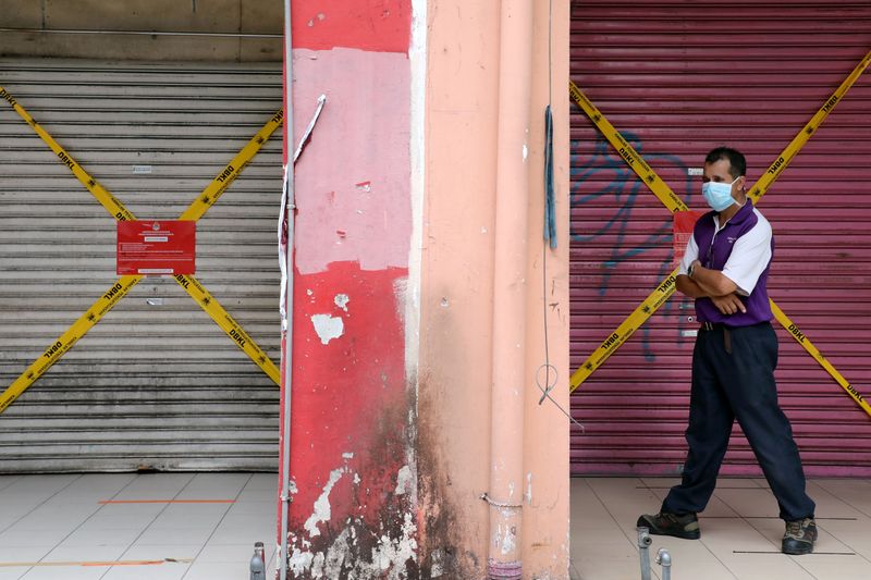 © Reuters. FILE PHOTO: A man wearing a protective face mask walks past closed shops, amid the coronavirus disease (COVID-19) outbreak in Kuala Lumpur