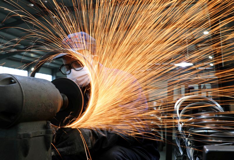 &copy; Reuters. FILE PHOTO: Worker wearing a face mask works on a production line manufacturing bicycle steel rim at a factory in Hangzhou, Zhejiang