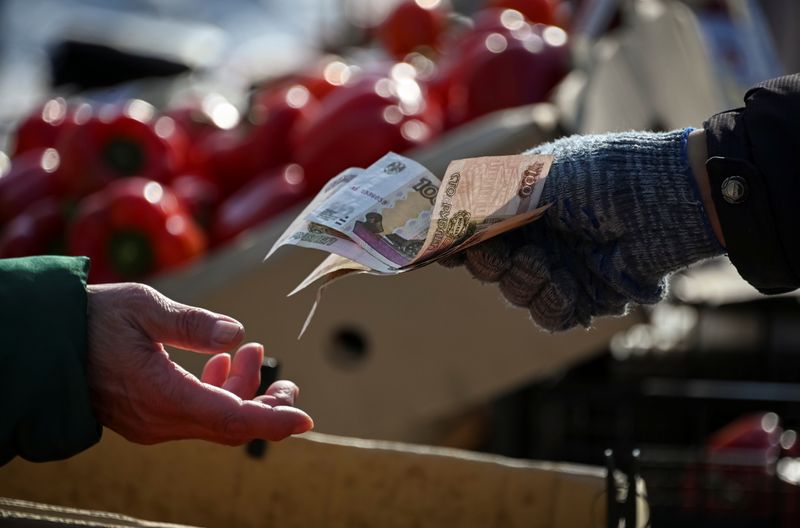 &copy; Reuters. A vendor hands over Russian rouble banknotes to a customer at a street market in Omsk