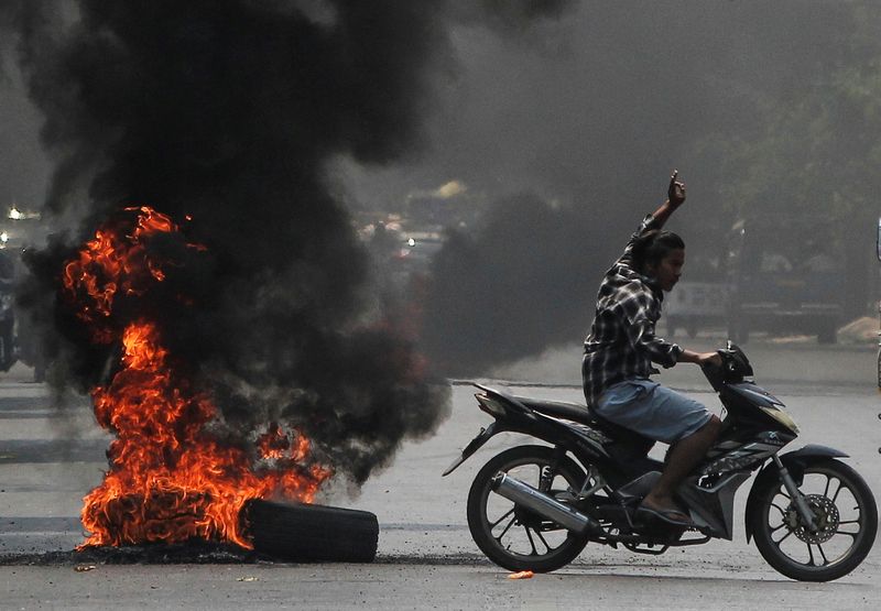 © Reuters. Man flashes three-finger salute next to burning tires during a protest against the military coup, in Mandalay