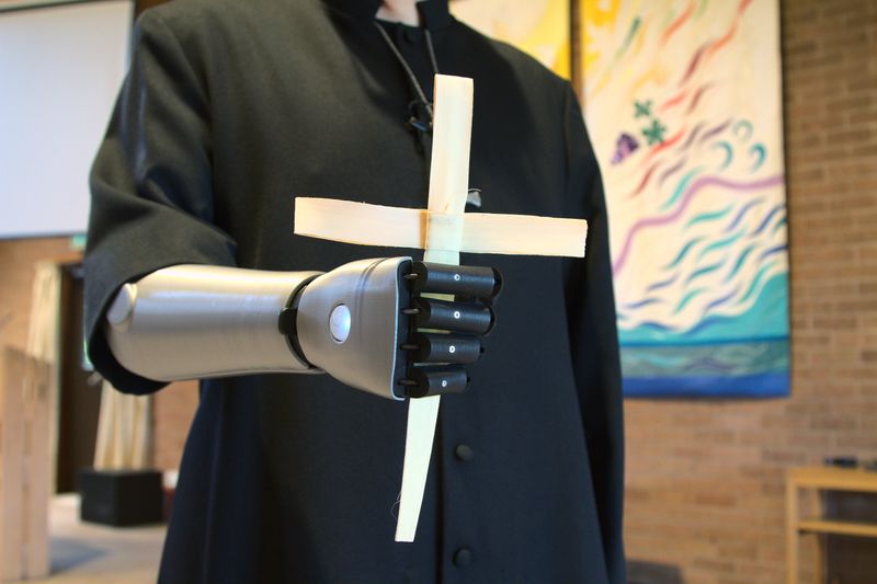 &copy; Reuters. Priest-in-training Daniel Cant holds a cross as he demonstrates his bionic arm by British company Open Bionics at Christ Church in Colchester