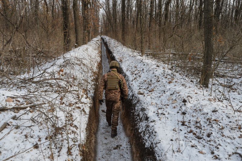 © Reuters. FILE PHOTO: A Ukrainian service member walks along fighting positions near Avdiivka
