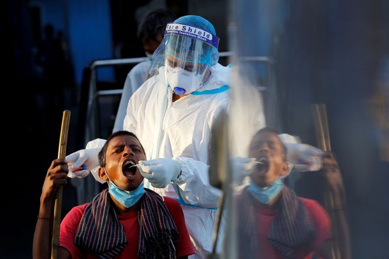 &copy; Reuters. FILE PHOTO: Healthcare worker collects COVID-19 test swab sample from man in New Delhi
