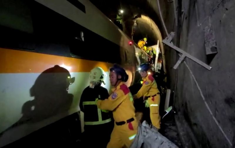 &copy; Reuters. Trabajadores de rescate caminan junto al tren dañado que descarriló en un túnel al norte de Hualien