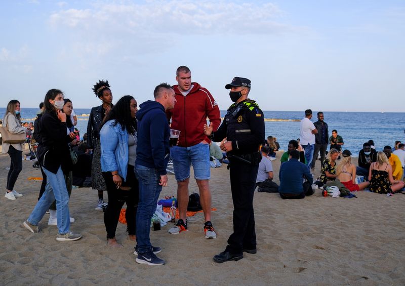 &copy; Reuters. A police office speaks with tourists after vacating a party at Barceloneta beach, in Barcelona