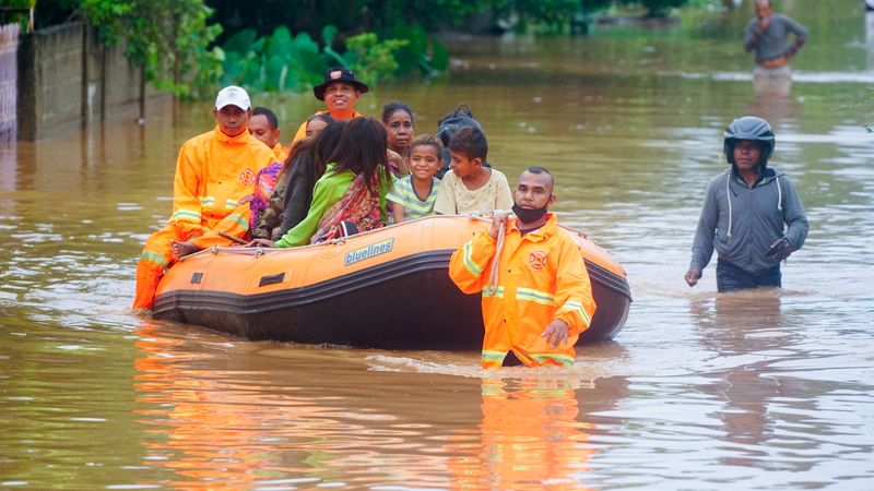 © Reuters. Rescue workers evacuate people through the water in an area affected by floods after heavy rains in Dili