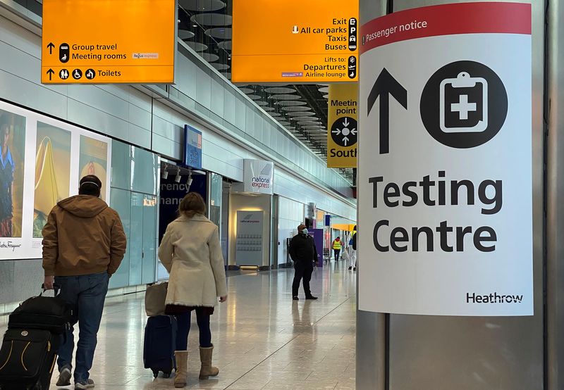 &copy; Reuters. Travellers pass a sign for a COVID-19 test centre at Heathrow Airport